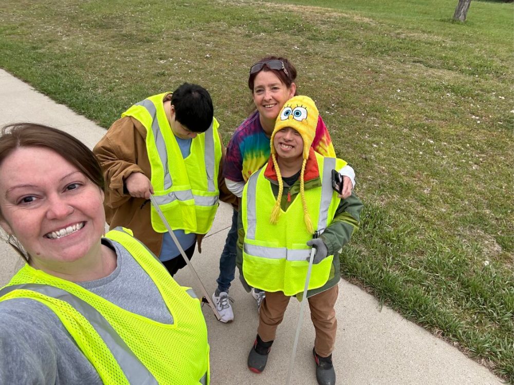 Staff and people supported outside on a sidewalk to clean up trash.