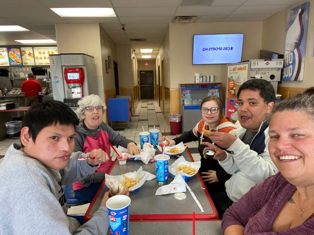 A group of staff and people supported seated at a lunch table having lunch at Dairy Queen.