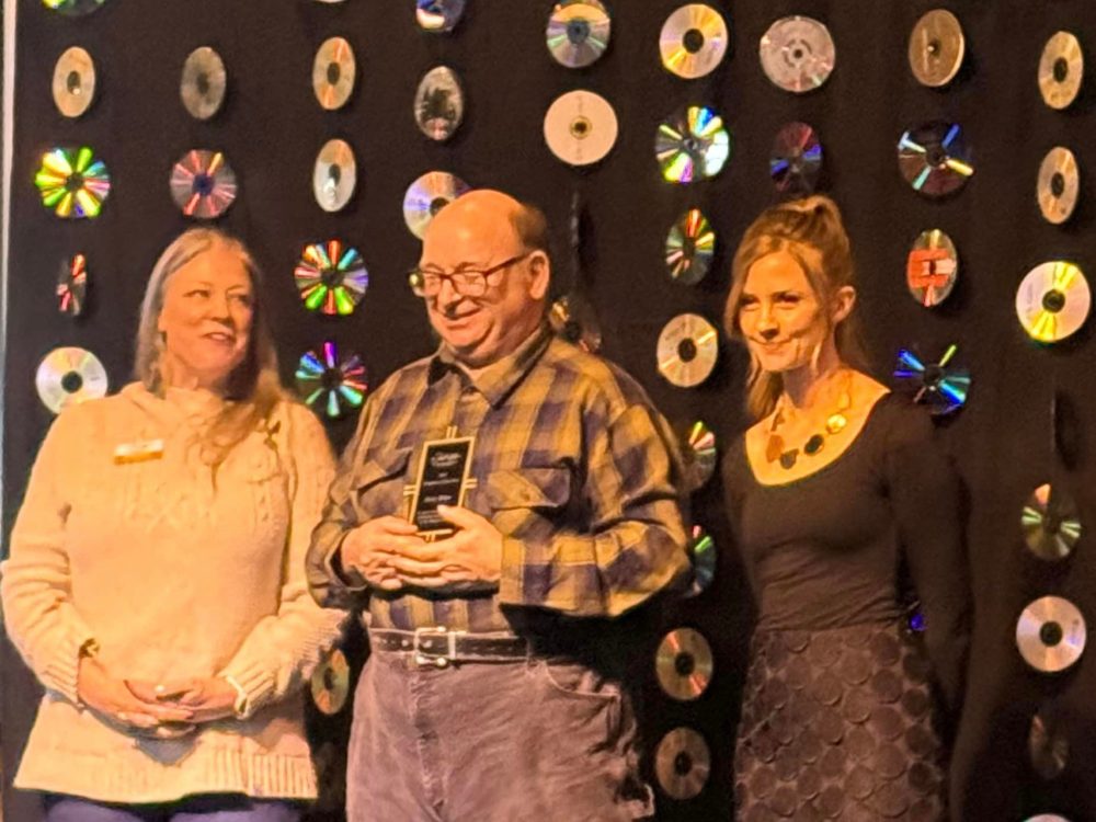 Three individuals on stage at the Sturgis Chamber of Commerce Awards Celebration.