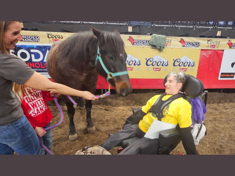 woman in a wheelchair next horse in the ring at the Special Rodeo